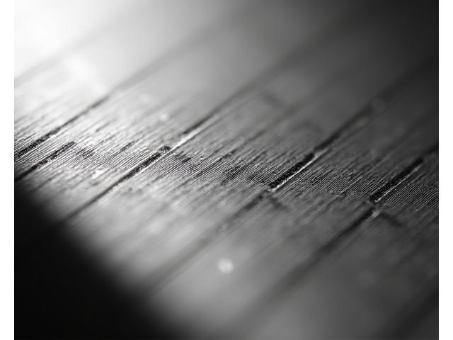 Makro záběr laserového gravírování s vysokou přesností na titanovém povrchu Apple Watch, zvýrazňující jemnost linky.